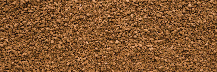 Dry brown granules of instant coffee background. Closeup. Wide banner. Empty place for text. Top down view.