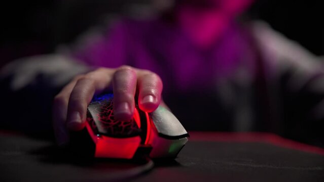 Close up shot of gamer clicking pc mouse button. Teenager boy plays computer video game in dark room, cybersport gaming, children gaming addiction