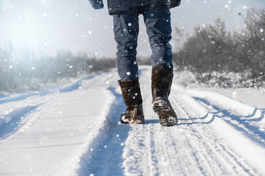 A traveler in boots walks along a snowy winter road