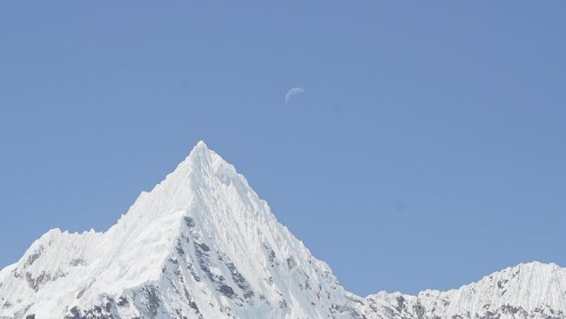 ice covered glacier of a pyramid shaped mountain at laguna paron lagoon in the high andes mountains of the cordillera blanca at huascaran, Peru, with snow covered mountain peaks on a bright sunny day.