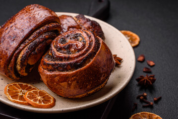 Delicious fresh sweet baked buns with poppy seeds and cinnamon on a ceramic plate