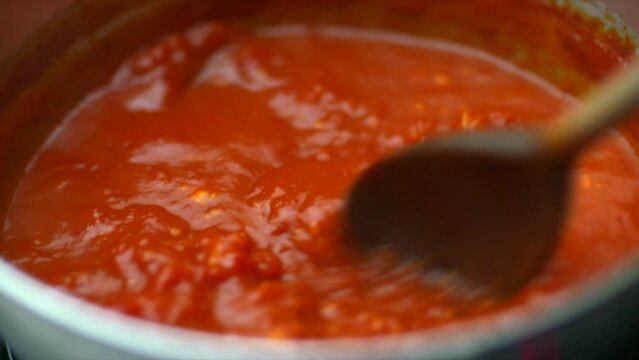 Tomato Sauce stirred in saucepan. Pasta suace in pan stirring. Footage of tomato cooking in HD shallow depth of field. Footage of wholefood vegen vegetarian plant-based cook.