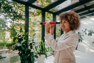 Smiling young businesswoman looking through hand-held telescope in office