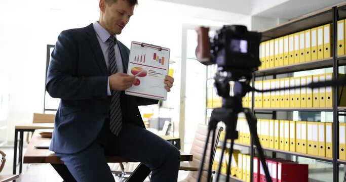Male entrepreneur records video lectures on business courses. Man professional shows graphic analyzing business proposal in business field