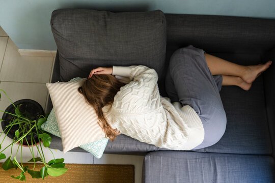 Woman with stomach cramp sleeping on sofa at home