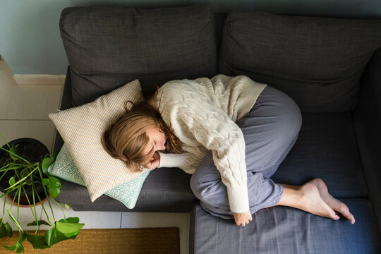 Woman with stomachache sleeping on sofa at home