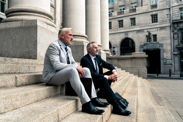 Thoughtful businessman sitting with colleague on steps
