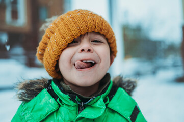 Playful boy wearing warm clothes sticking out tongue in winter