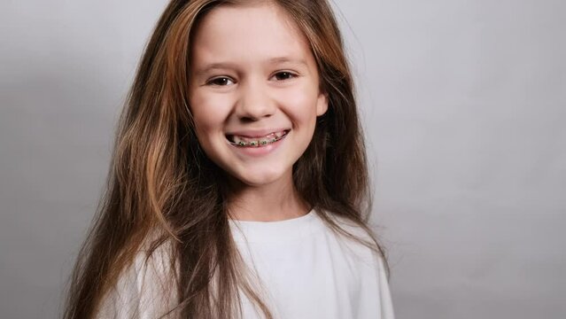 Joyful emotion of a young beautiful girl with long brown hair and braces. Happiness concept.