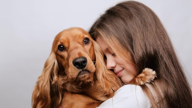 A beautiful girl holds her beloved dog in her arms and hugs it. Friendship concept with pet.