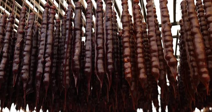 Georgian red sweets churchkhela hanging on strings at tourist market. Homemade flavor organic dessert sold at seaside resort town market against sky
