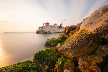 Poster Sunken ship washed up on the seaside, sunset. © Samet
