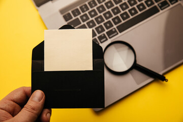 Envelope with blank card, magnifier and keyboard on yellow background