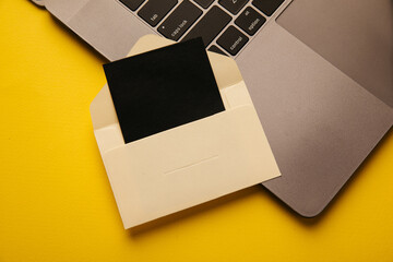 Paper envelope with card and laptop on a yellow background