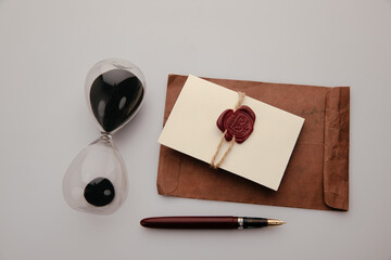 Paper envelope with red wax seal and hourglass