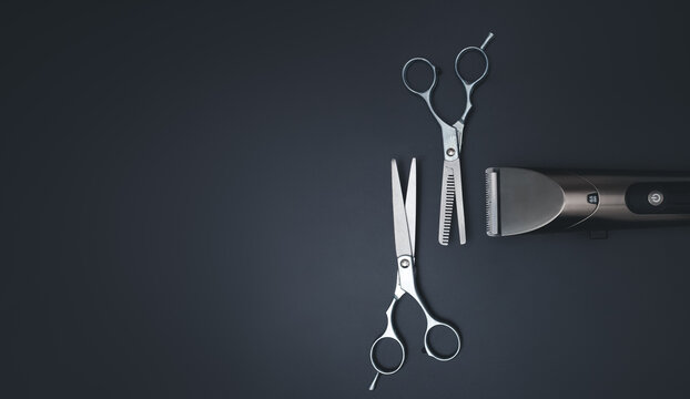 Stylish professional barber scissors, Hairdressing scissors and Machine for a hairstyle on black background. Various shaving and bauty care accessories placed on black background.