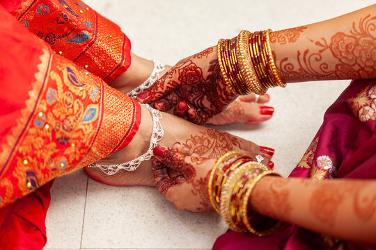 Indian Wedding Ceremony Concept. An Indian bride gets her silver anklets put on by another woman.