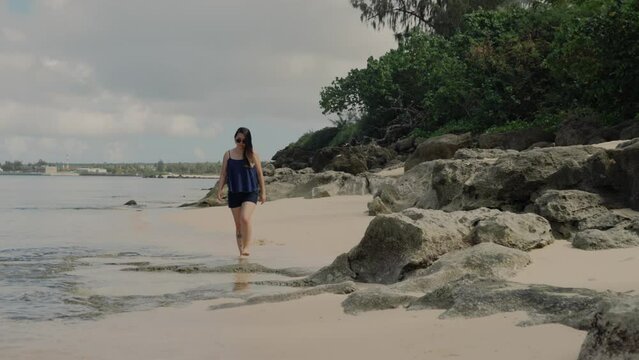 Front view of girl walking on the beach during a sunny and bright morning