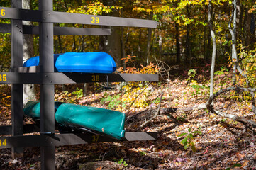 Wooden racks of colorful kayaks in the lush woods. Idyllic outdoor rustic nature sporting background French Creek State Park Pennsylvania