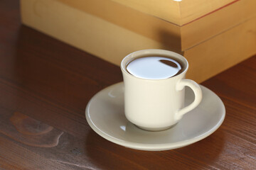 cup of coffee and books on wooden table. 