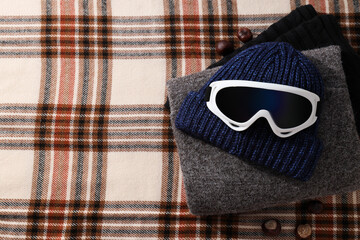 A warm knitted hat with ski goggles and a hood