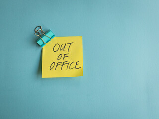 Out of office, message on yellow paper and blue background.