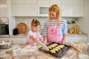 Mother and daughter baking homemade croissants in the kitchen