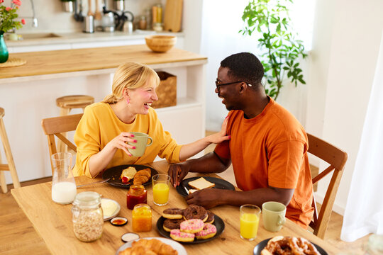 Multiracial couple enjoying breakfast together at home - Powered by Adobe