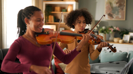 Mother and teenage boy playing violins at home