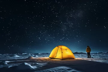 Fotobehang Illuminated yellow tent at night in snowy mountains with person standing next to it and starry sky, long night exposure of tent in mountains.generative ai  © Ivan