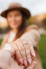 Man proposing to woman in autumn park. Marry me. Romantic photo of  charming woman. Male holding woman's hand with a wedding ring on her finger. Vertical frame.