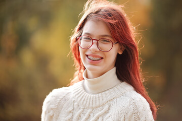 Beautiful smiling teenage girl with long red hair. Autumn colors.