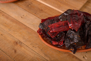 Ancho chili and guajillo chili in a clay dish on a wooden table. Chilies prepared to make red sauce.