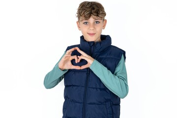 Serious  caucasian kid boy wearing blue vest  keeps hands crossed stands in thoughtful pose concentrated somewhere