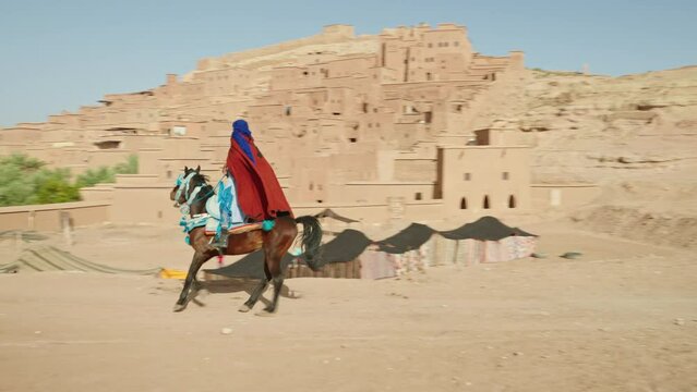 Man riding his horse in front of Ait Benhaddou old town, Morocco