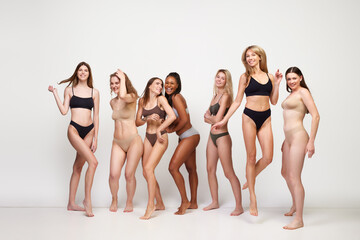 Happy positive young women of mixed race, different age, skin color and body shapes standing in...