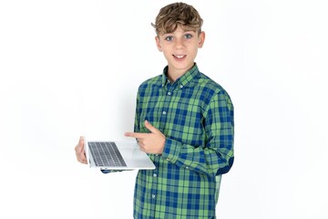 Shocked caucasian kid boy wearing plaid shirt pointing finger modern device