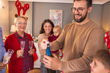 Man opening bottle of champagne while celebrating New Year with family at home