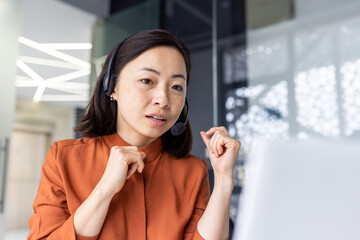 Serious Asian woman listening online conversation close up, businesswoman with headset phone, online customer support worker, working with laptop, video call consultation.