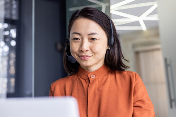 Serious Asian woman listening online conversation close up, businesswoman with headset phone,...