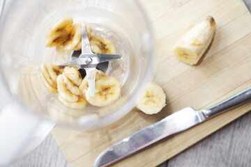 Banana shake in blender. Banana slices inside kitchen blender. Banana smoothie recipe background....