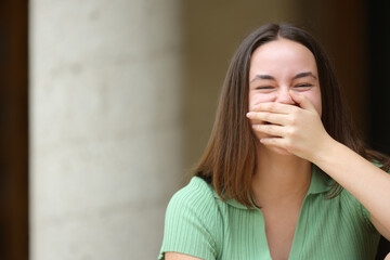 Happy woman laughing covering mouth looks at you