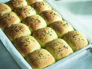 golden brown baked green dinner bread rolls with black sesame seed topping