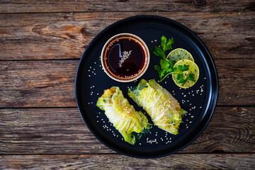 Stuffed Asian cabbage rolls and soy sauce on wooden background