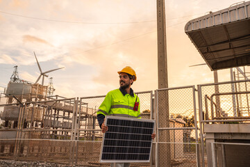 Engineer wearing uniform holding solar panels and inspection work in wind turbine farms at sunset...