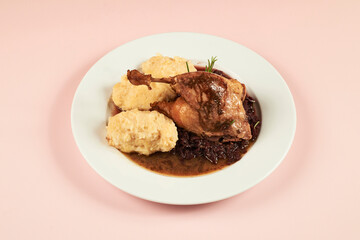 Delicious roasted goose leg with stewed cabbage and mashed potatoes close-up in a plate on the table. horizontal