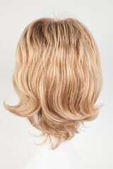 Naklejka premium Natural looking blonde fair wig on white mannequin head. Short hair cut on the plastic wig holder isolated on white background, back view.