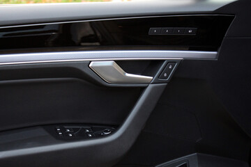 Premium Car door leather trim with windows control. Lux Car Inside Door Handle Interior. Door black leather trim. Front door leather trim of a Prestige car. Modern Car interior. Driver seat memory.
