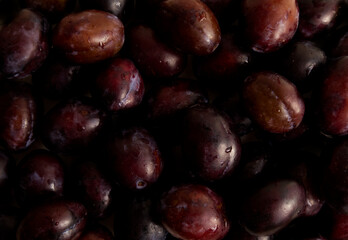 Ripe plums with drops laid out on the surface as a background close-up
