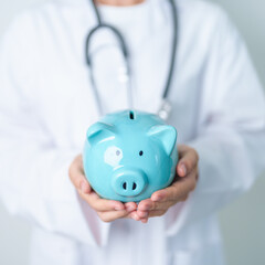 Doctor holding piggy bank and putting coin. and Healthcare cost, Money Saving, Health Insurance, Medical, Donation and Financial concepts